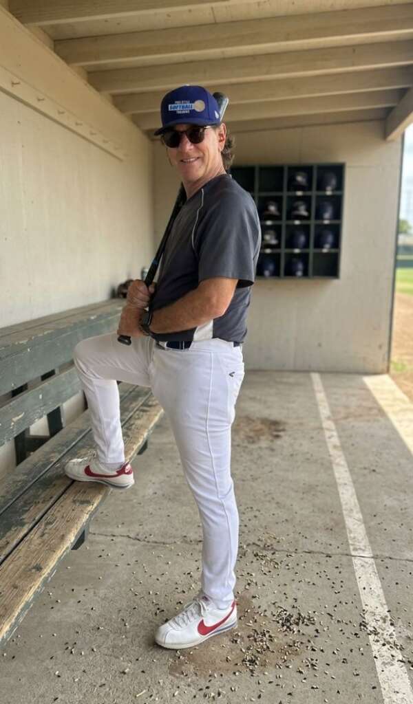 darren-elliott-posing-with-a-bat-in-hand-with-one-foot-on-the-dugout-bench